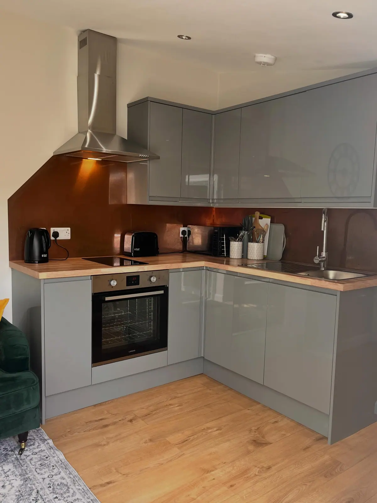 Compact fitted kitchen with copper-toned splashback